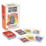 Exploding Kittens card game set with a cream and orange box, a red deck box, and several illustrated cards arranged on a white background.
