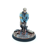 A painted tabletop miniature figurine of a soldier in a blue uniform with gold shoulder details, standing on a circular textured base against a white background.