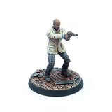 A painted tabletop miniature figurine of a man in a light beige jacket and dark pants, holding a pistol, standing on a circular brick-patterned base against a white background.