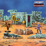 Toy figures on a miniature landscape with 'Masters of the Universe Battleground' branding.