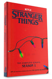 Red book titled 'Stranger Things' with Netflix branding and Christmas lights on a white background