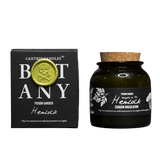 A jar candle and its box from Cantrip Candles Botany's Poison Garden, featuring Hemlock scent. The product consists of a dark amber glass jar with a cork lid and a black label, next to its black packaging box with a gold wax seal.