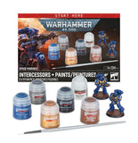Warhammer 40,000 Space Marines paint kit with multiple small paint bottles, a brush, and two painted blue intercessor miniatures displayed in front of the product box on a white background.