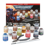 Warhammer 40,000 paints + tools set featuring a collection of 13 miniature paint bottles, pliers, a fine-tip brush, and a metal moldline remover, arranged in front of their retail box on a white background.