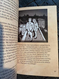 Open book with a black and white illustration of two people on a rooftop.