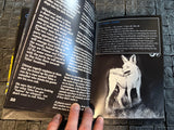Open book with a wolf illustration on a stone surface