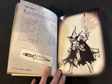 Open book with illustrations of a character and weapon, held by a hand.