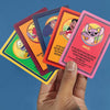 Hand holding colorful trading cards with cartoon characters against a blue background