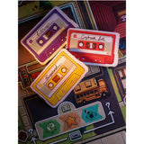 Colorful cassette tape-shaped patches on a textured surface with game pieces.