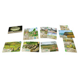 A set of illustrated game cards arranged on a plain white background. The cards feature scenic landscape artwork and game-related text, with no people, animals, or real environment visible.