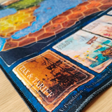 Close-up of a board game with cards featuring a ship illustration and 'Tax & Tariff' text.