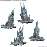 Four unassembled and unpainted miniature rock structures on a white background