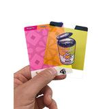 A hand holding three colorful cards against a plain white background. The cards are labeled 'Magenta', 'Orange', and 'Tomato Soup', with one card showing an illustration of an open tomato soup can.