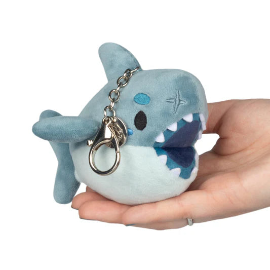 Plush shark keychain held in a hand against a white background