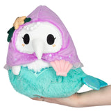Plush toy resembling a mermaid with a purple hood and green tail held in a hand on a white background