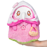 Plush toy owl in a pink outfit with a cherry blossom design, held by a hand on a white background.