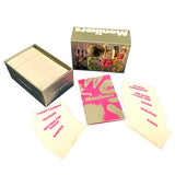 The 'Monikers' card game set displayed on a clean white background, including the olive green box, the deck of cream-colored cards, a pink and gold booklet, and several individual cards showing pink text on cream backgrounds.