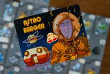 Astro Burger card with an astronaut and spaceship design on a blurred background