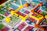 Close-up of a colorful board game with various colored pieces on a board featuring different sections.