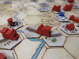 Board game with hexagonal tiles and red player pieces on a map.