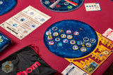 Board game setup on a red table with various game pieces and cards.