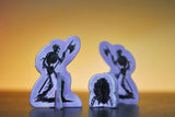 Three purple silhouette figures with black details on a reflective surface and gradient background