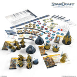 StarCraft tabletop game components including miniatures, cards, and rulebooks on a white background.