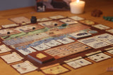 Board game with cards and pieces on a wooden table, candle in the background
