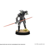 A painted sci-fi miniature figurine of a green-skinned soldier in dark gray armor, holding a long orange-red sword, mounted on a black round base with faux grass and gravel, on a white background.