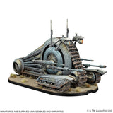 A painted sci-fi miniature model of a large tracked vehicle or siege machine, shown assembled on a display base against a plain white background. The model features metallic gray and silver armor with dark brown tracks and small orange light details.