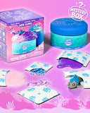 Dope Slimes by Slime World 'Oceanic Series 1' Mystery Box set, featuring a blue and teal jar, its illustrated packaging box, and several unsealed foil packets containing pink slime, blue beads, purple slime, and a small blue creature toy, all arranged on a pink ocean-themed background.