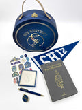 Collection of Shiz University-themed stationery items including a blue hat box, pen, notebook, and stickers on a white background.