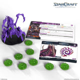 StarCraft tabletop game components including a purple creature figure, cards, and green game pieces on a white background.