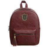 Harry Potter Gryffindor Mini Backpack. A front facing picture showcasing the stamped burgandy faux leather. A small metal crest depicting the Gryffindor is placed in the middle of the biggest pocket. Then a smaller pocket in front with a matching tassel on the zipper. Both pouches only have one zipper each.